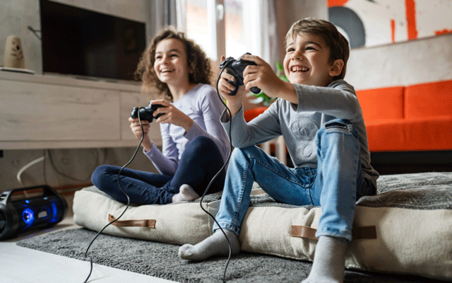 two kids smiling with game controllers